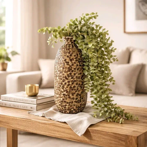 A 42-inch artificial hanging eucalyptus stem with cascading soft green leaves displayed in a decorative vase on a wooden table, creating a fresh farmhouse-inspired look.