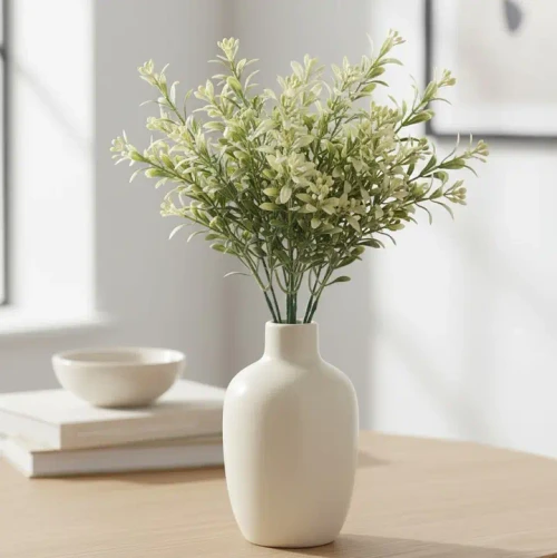 A 13-inch decorative faux floral stem featuring clusters of delicate, creamy vanilla-white blossoms and soft green leaves attached to a slender, pliable brown branch.