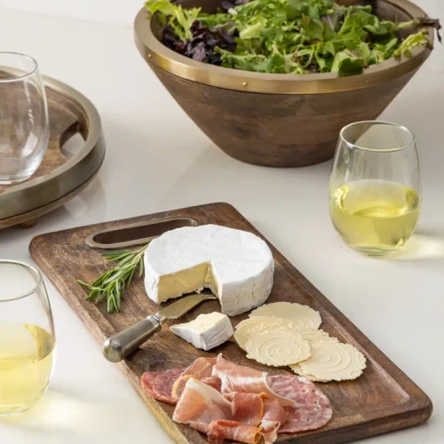Rustic mango wood serving tray filled with appetizers paired with its matching stainless steel serving knife.