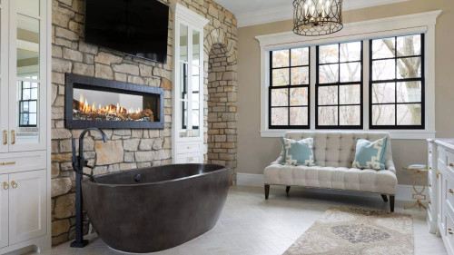 Front view of a Heat & Glo Mezzo 36-inch see-through linear direct vent natural gas fireplace showcasing a modern ribbon flame extending across a glass media bed, visible from two sides.