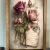 Rustic farmhouse wall sign featuring soft pink and mauve vintage roses arranged over an antique handwritten letter with vintage postage stamps and a delicate feather in a natural wood frame.