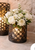 decorative black metal lantern with pillar candle displayed on a stone fireplace hearth, accented with white floral arrangements.