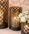 decorative black metal lantern with pillar candle displayed on a stone fireplace hearth, accented with white floral arrangements.
