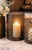 decorative black metal lantern with pillar candle displayed on a stone fireplace hearth, accented with white floral arrangements.
