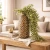 A 42-inch artificial hanging eucalyptus stem with cascading soft green leaves displayed in a decorative vase on a wooden table, creating a fresh farmhouse-inspired look.