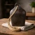 An antique-style iron bell featuring a weathered, dark finish and a rustic hanging rope. The piece measures 3 inches wide by 4 inches high, offering a classic farmhouse look perfect for tabletop or mantel displays.