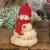A soft plush snowman decorative figurine designed in a playful melting puddle style. It features a plush white body with dark coal button accents, an orange carrot nose, and a cozy red knit winter hat with a plush brim and festive trim.