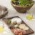 Rustic mango wood serving tray filled with appetizers paired with its matching stainless steel serving knife.