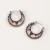 Close-up view of intricate burnished metal crescent hoop earrings displayed on a neutral background.