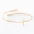 Close-up view of a gold cross bangle bracelet featuring an extended cross design cuff, displayed against a clean neutral background.