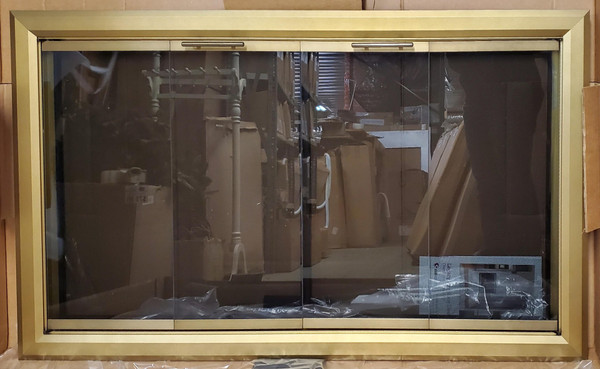 Clearance Custom Glass Fireplace Door (CL142) highlighting a wide, premium Bifold Legacy Lancaster frame in an elegant Vintage Brass finish with built-in cabinet mesh.
