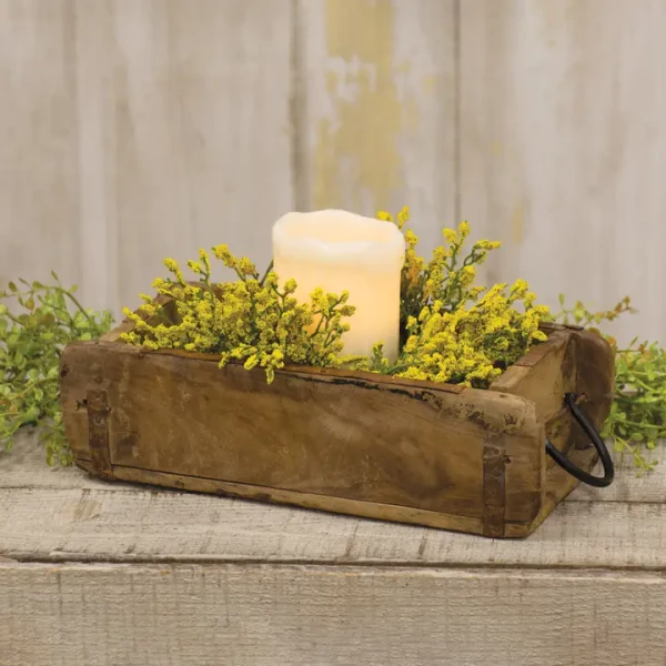 Rustic weathered wooden brick mold box with iron hardware accents, shown holding a pillar candle and green foliage.