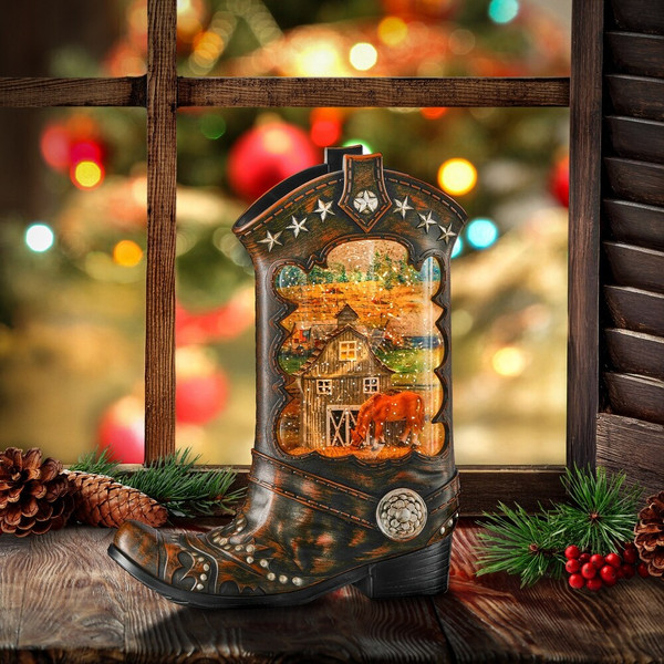 A western-themed holiday waterglobe shaped like a detailed, dark brown cowboy boot decorated with festive country holiday artwork and illuminated from within.
