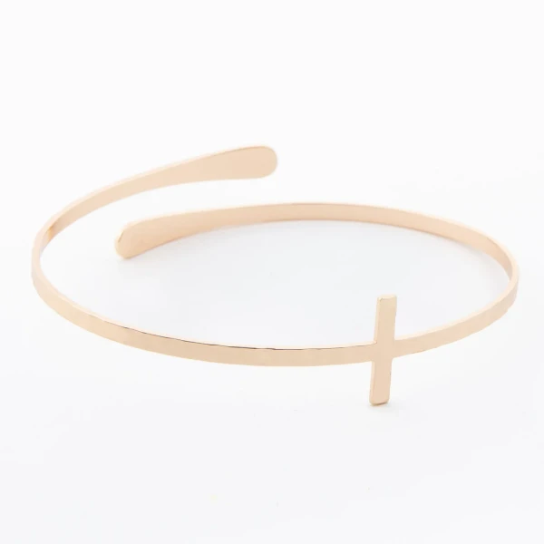 Close-up view of a gold cross bangle bracelet featuring an extended cross design cuff, displayed against a clean neutral background.
