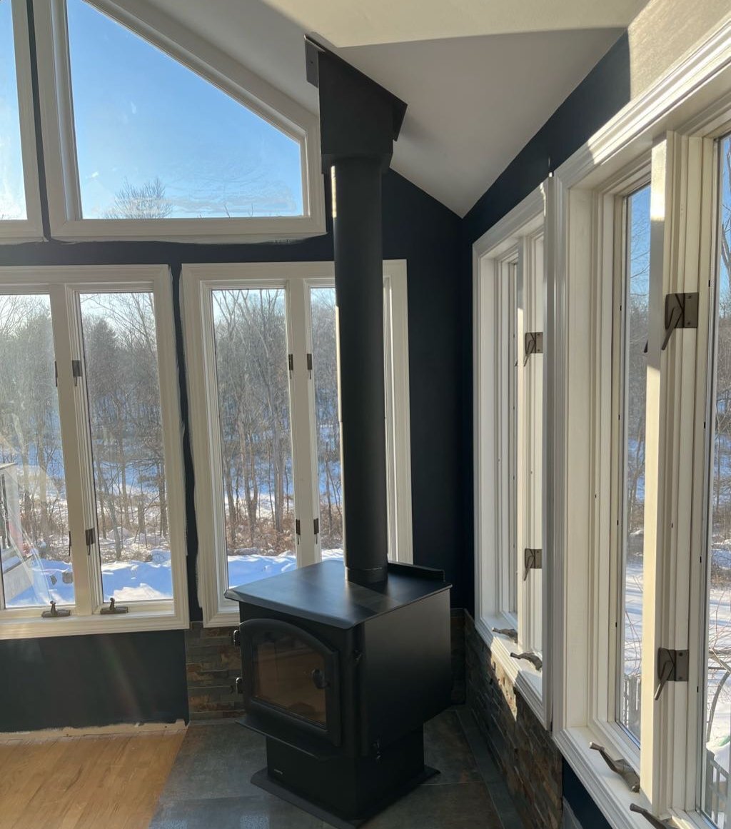 Quadra-Fire steel freestanding wood stove installed in a Connecticut sunroom with a snowy winter view