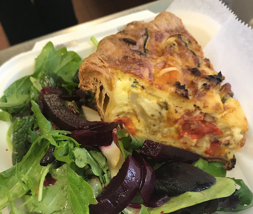 Slice of quiche with salad in takeout container