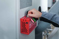 ABUS B835 Safety Redbox mounted on industrial equipment panel, technician inserting key to open lockout box in facility setting