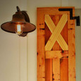 Delaney Hardware Exterior Shutter Blind Hinge installed on wood board-and-batten shutter mounted on exterior wall beside vintage wall sconce light fixture