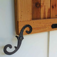Delaney S Hooks Exterior Shutter Blind Hinge installed on natural wood shutter panel against white siding, black iron finish, close-up view