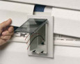 Arlington Industries Low Profile Electrical Outlet Box being installed into vinyl siding - Horizontal Clear Cover variant shown during new construction installation