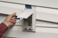 Arlington Industries Low Profile Electrical Outlet Box being installed into vinyl siding – Horizontal White Cover variant shown during new construction installation