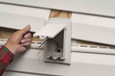 Arlington Industries Low Profile Electrical Outlet Box being inserted into rough opening in vinyl siding - White Cover variant shown at rough-in stage of new construction