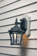 Arlington Industries Siding Mounting Kit installed on gray lap siding with black ornate outdoor lantern – close-up finished installation view