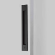 Emtek Modern Rectangular Flush Pull for Door Pull (Opposite Side) in Flat Black (US19), installed on a door edge — in-use lifestyle shot