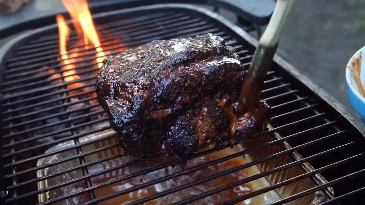 Pork shoulder cooking on a PK charcoal grill grate over live fire