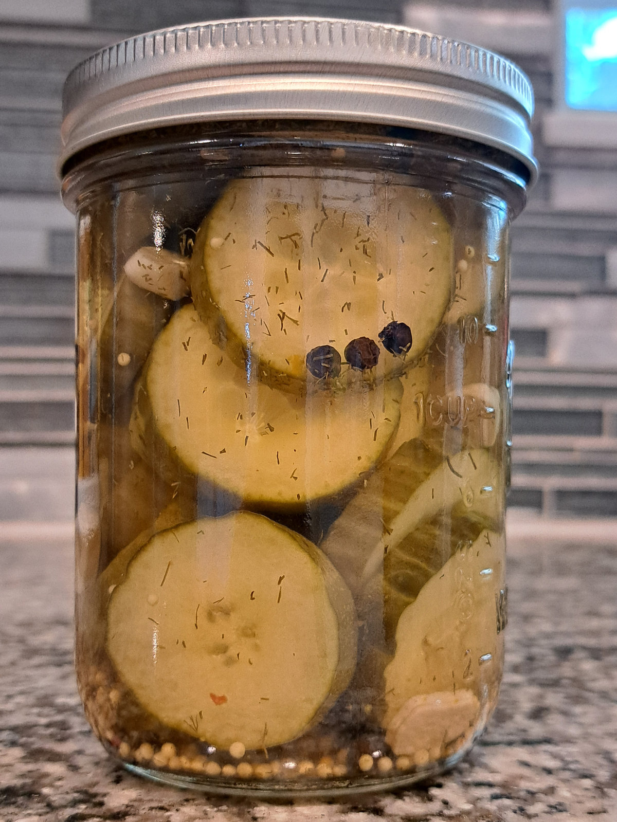 Jar of Small Batch TX Scorpion dill pickle chips with peppercorns