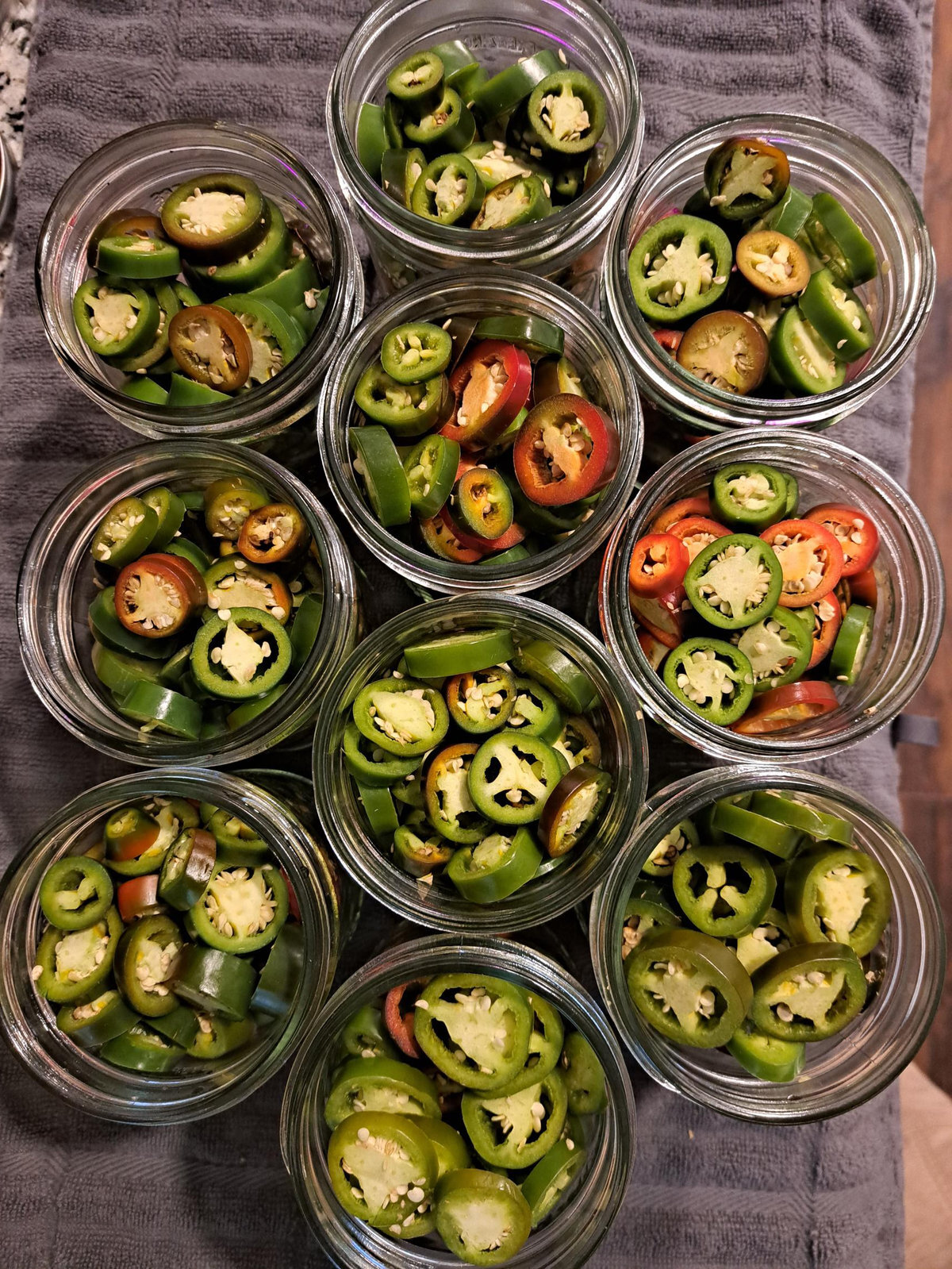 Small glass jars packed with freshly sliced green and red peppers