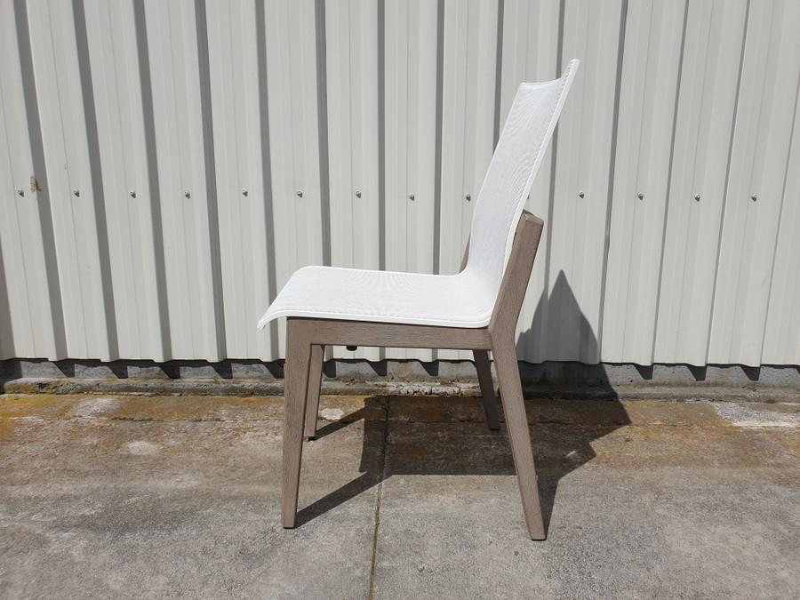 Side view of Copenhague outdoor dining  side chair by Les Jardins. Teak wood is finished in Duratek coating.  Batyline Eden sling seat.