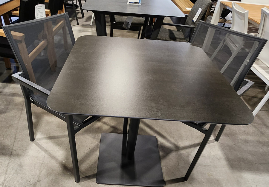 The MOON Cafe Table displayed here in our showroom with our AMAKA Dining Arm Chairs in Space Grey.