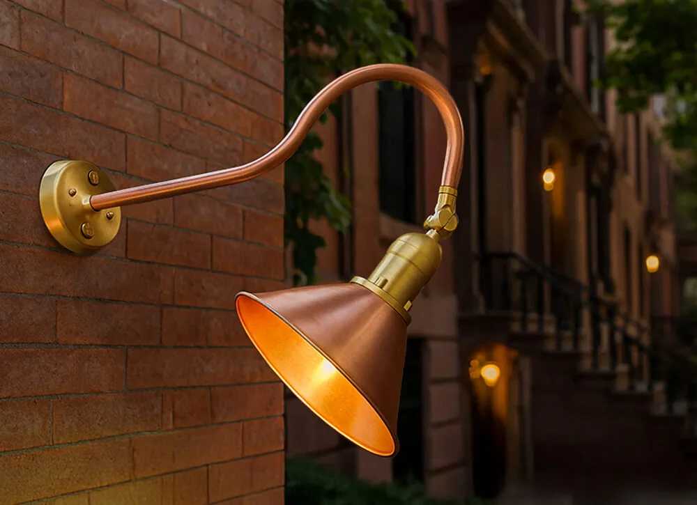 Raw copper gooseneck sign light on a brick wall