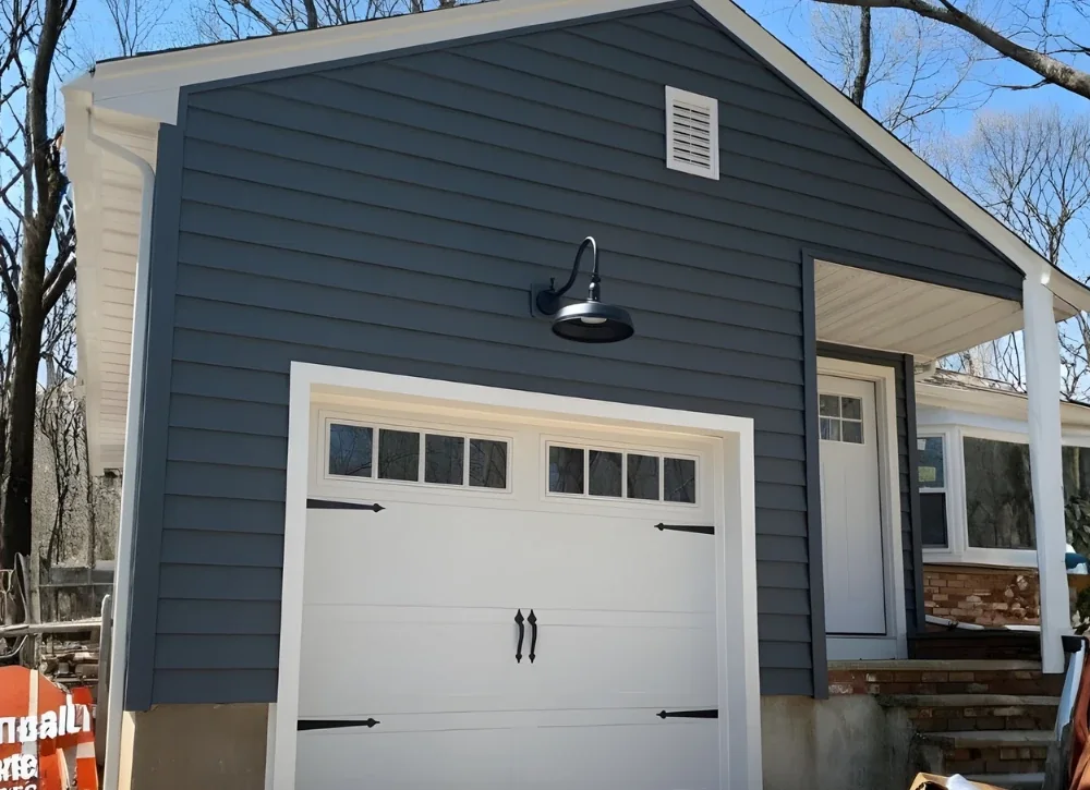 Black gooseneck barn light installed over a white garage door