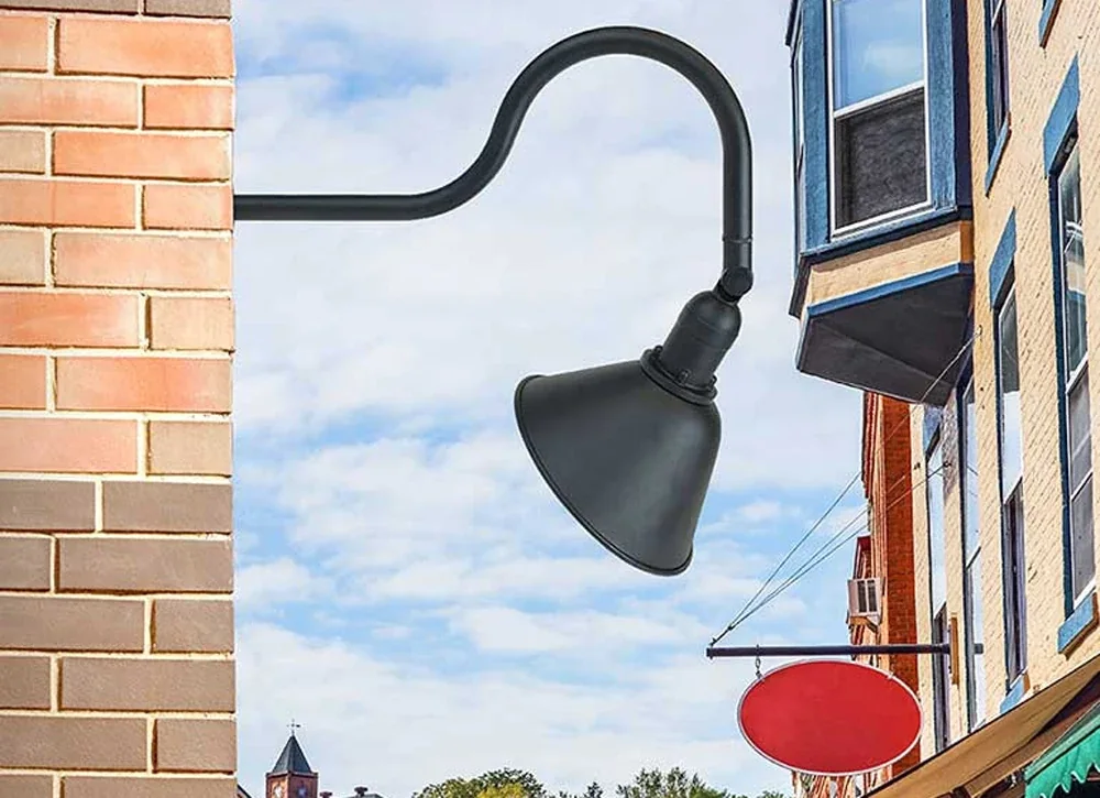Black gooseneck sign light on a brick storefront above a hanging sign