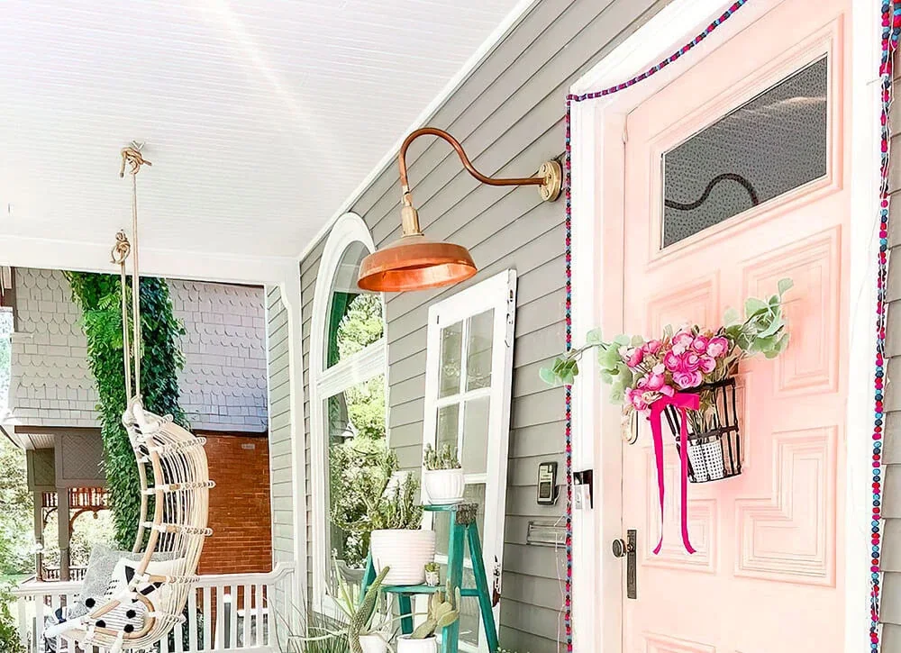 Raw copper gooseneck barn light over a front door on a white porch