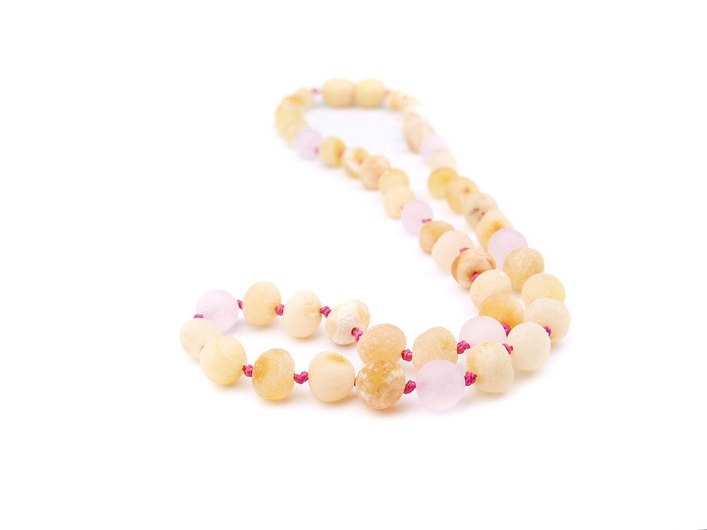 Natural Baltic amber teething necklace featuring raw butterscotch nuggets and matte pink rose quartz