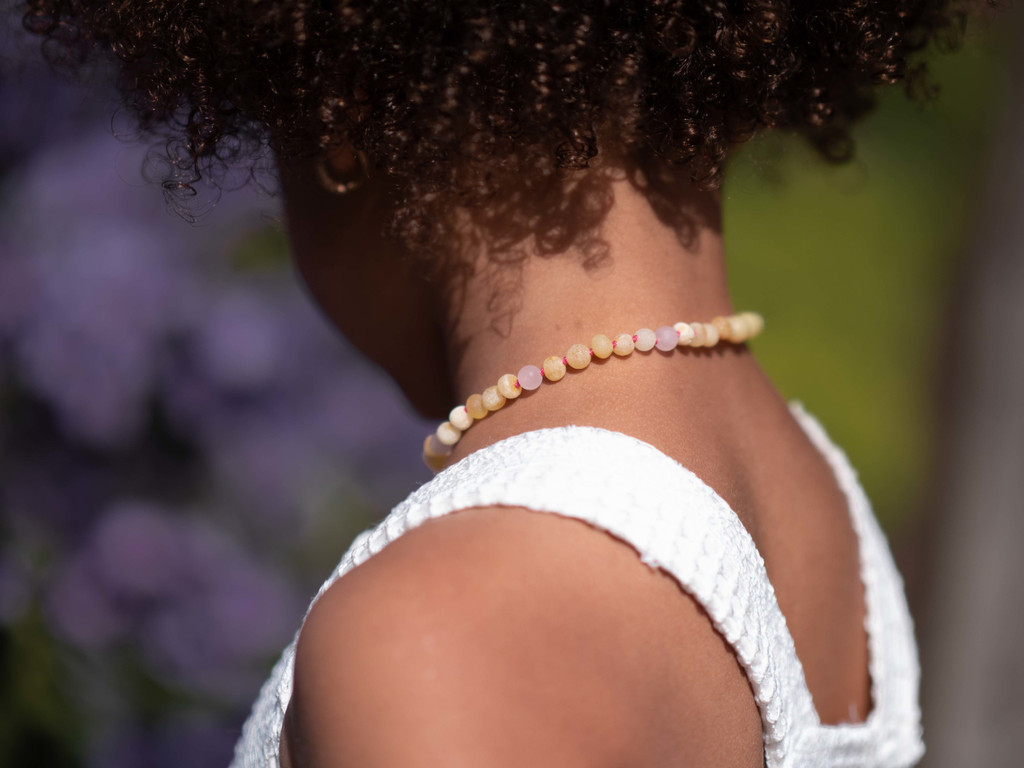 Natural raw Baltic amber teething necklace for kids featuring butterscotch nugget beads and matte rose quartz