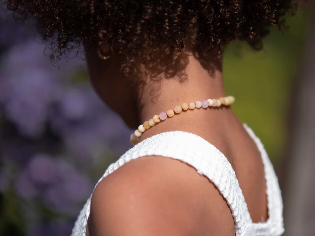 Natural raw Baltic amber teething necklace for kids featuring butterscotch nugget beads and matte rose quartz