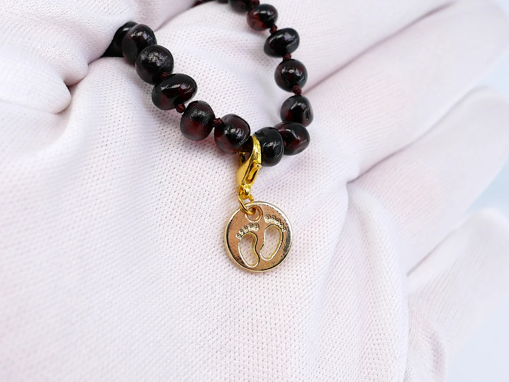 Gold Baby Footprint Charm Inspired by Amber Teething Jewellery – Baby-themed gold-tone pendant designed to complement traditional Baltic amber teething-style jewellery collections as a decorative keepsake for parents