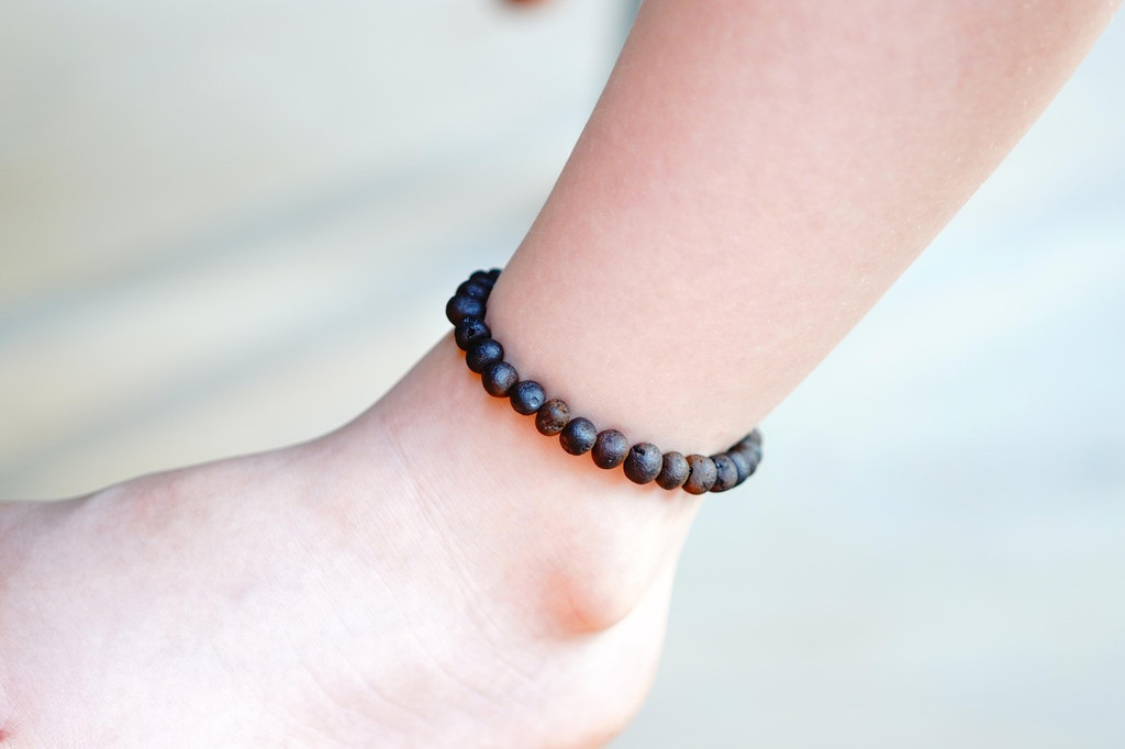 Handcrafted stretch Baltic amber teething anklet featuring dark cherry and black raw beads, made from genuine eco-friendly amber for everyday wear