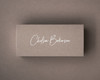 Mocha flat place card printed in crisp white ink with modern calligraphy, placed on a coffee-brown surface.