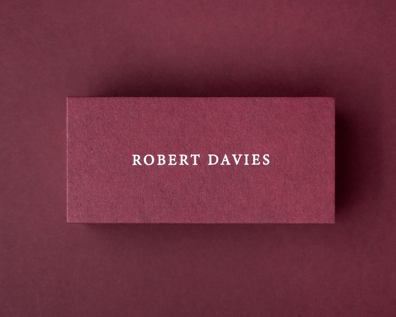 Custom burgundy flat place card featuring the name Robert Davies in white serif font, ideal for elegant table settings and luxury event stationery.