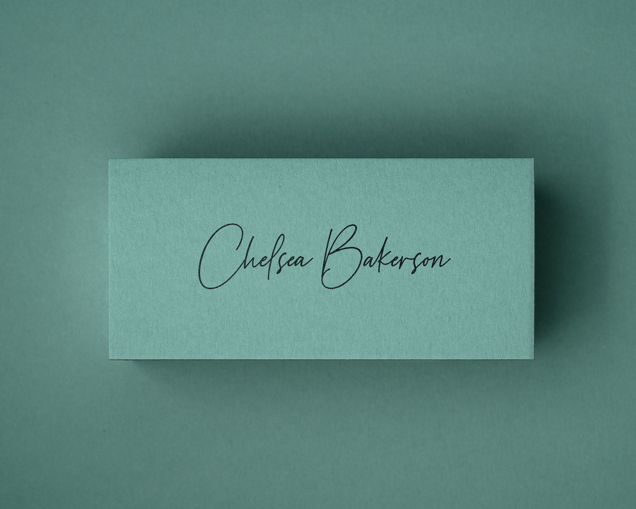 A personalised jade green place card printed in black ink in a delicate script font. The dark ink contrasts beautifully with the soft green backdrop, ideal for refined table settings or stylish event décor.