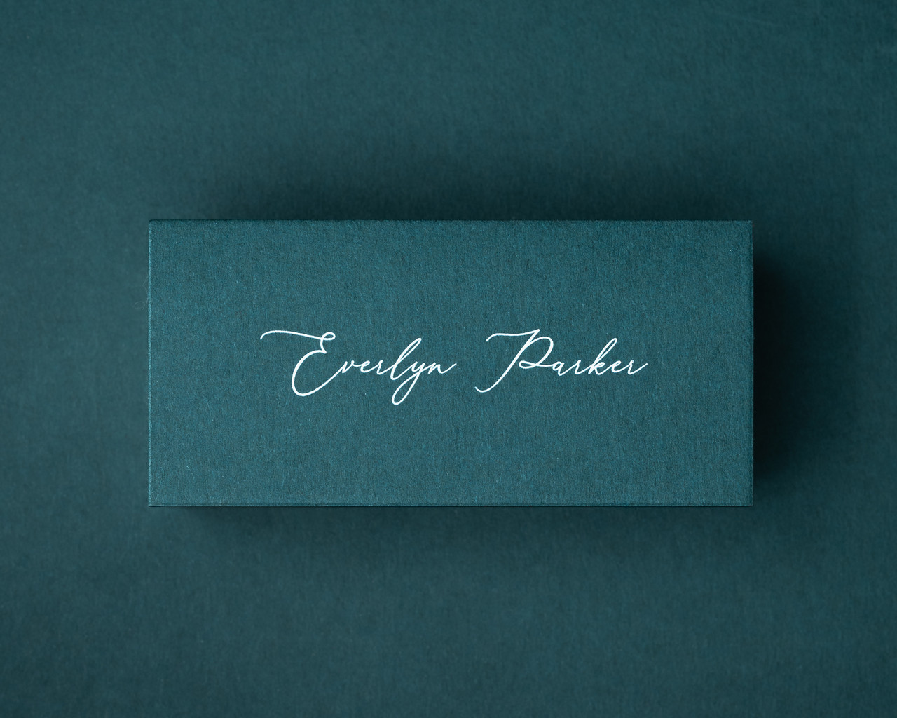 A personalised Hunter Green flat place card printed in white ink in elegant calligraphy.