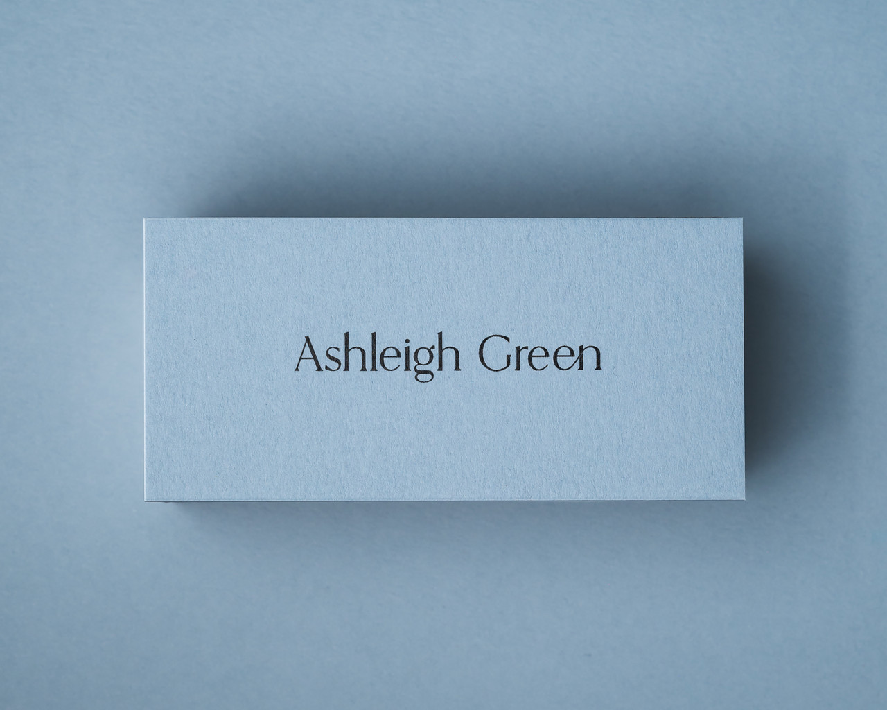 A personalised Dusty Blue place card printed with black ink in a modern calligraphy font.