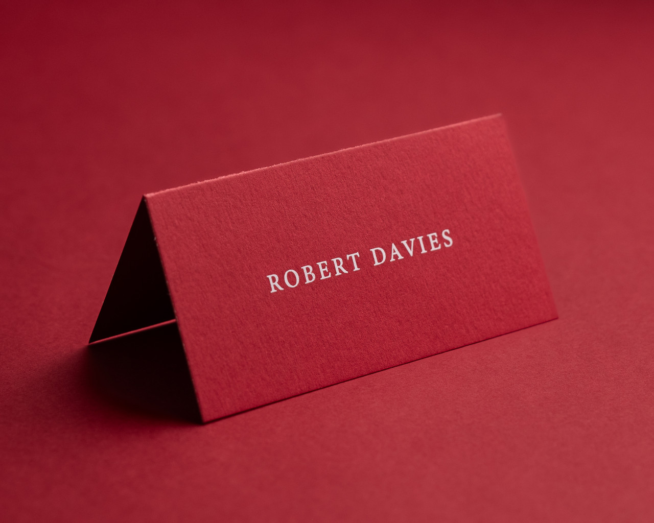 Personalised cherry red folded place card with white ink printing.