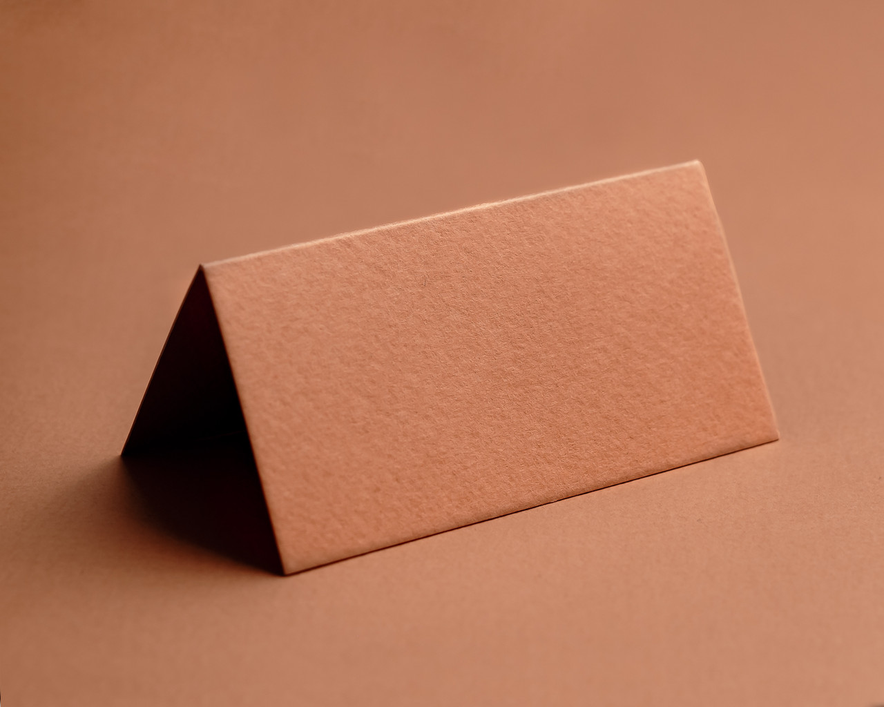 Blank terracotta folded place card on matching background – luxury 350gsm rustic card.