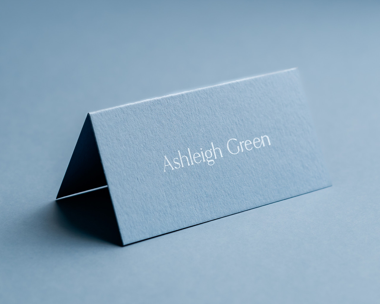 Personalised dusty blue folded place card with white ink name printing, luxury 300gsm wedding stationery